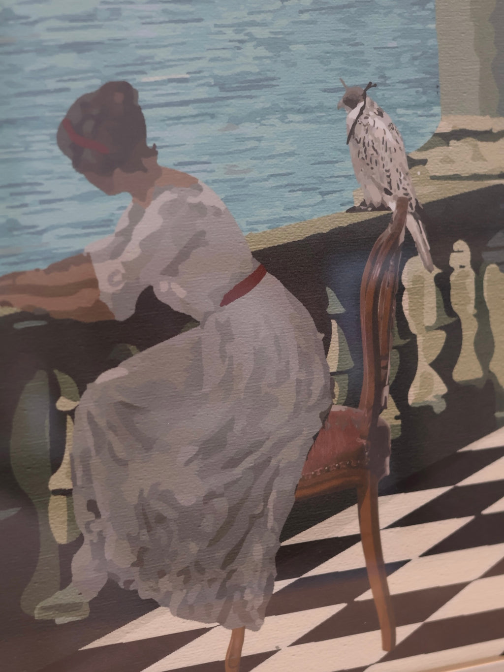 A woman in a long white dress seated on a wooden chair by a waterfront, with a falcon perched on the back of the chair. 