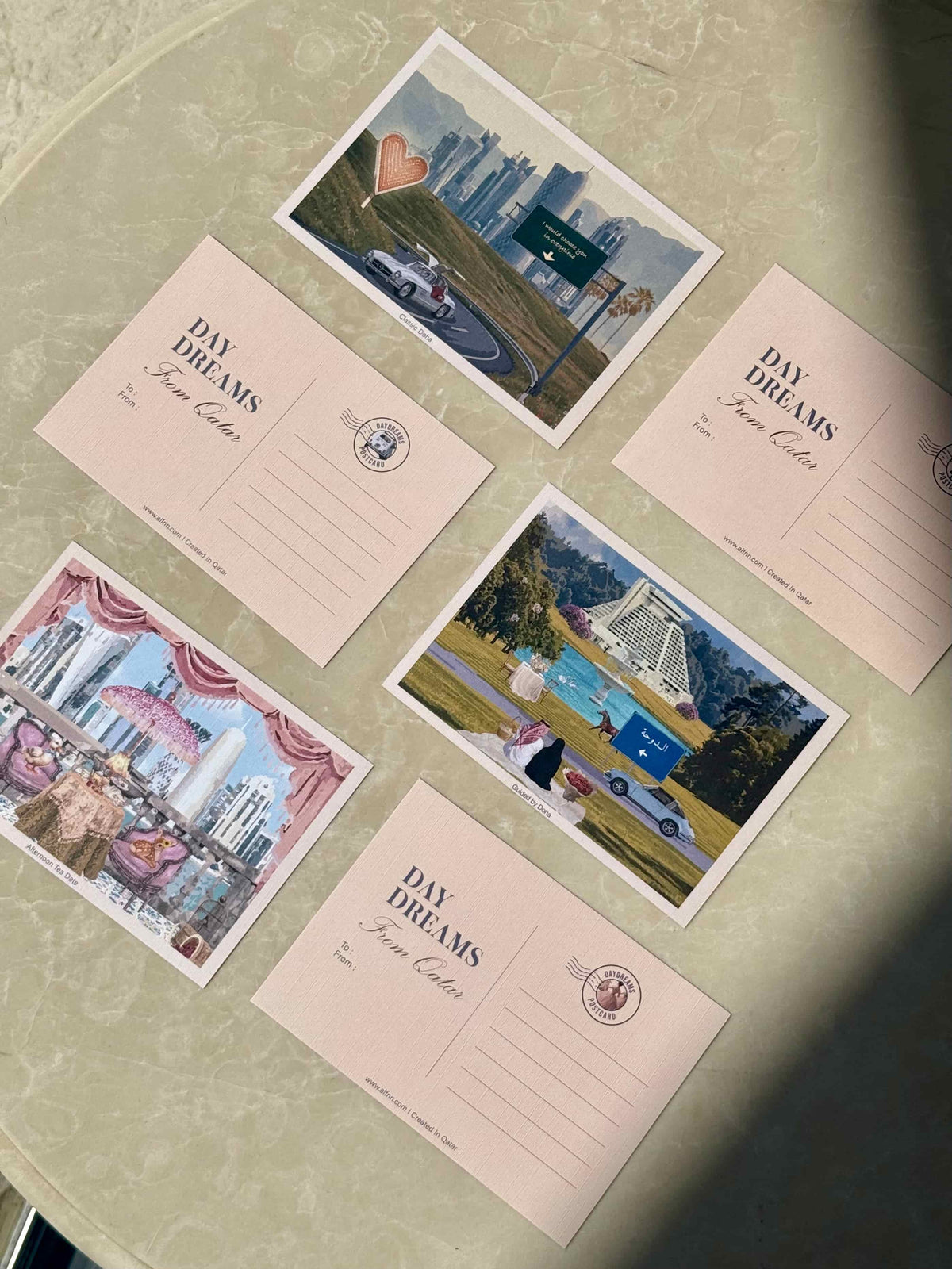 Six postcards with pastel pink fronts and colorful scenic art.The postcards feature scenes in Qatar, the city skyline, roads,and romantic Doha Scenes.